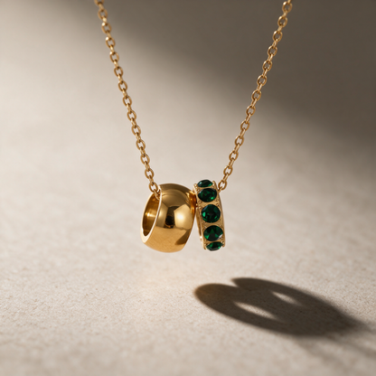The Linked Birthstone Necklace in dark green — two interlocking rings pendant, one solid and one crystal, on a fine chain.