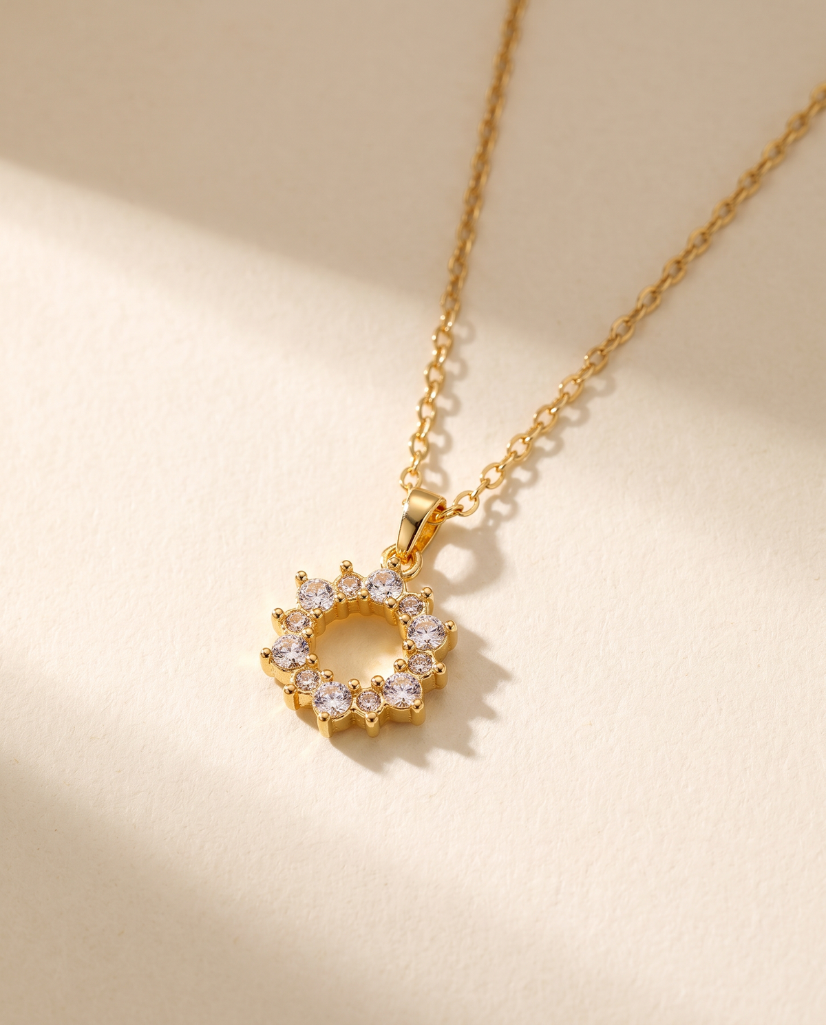 Geometric Ring Pendant Necklace in gold — stainless steel with 18K gold plating, on a plain ground.
