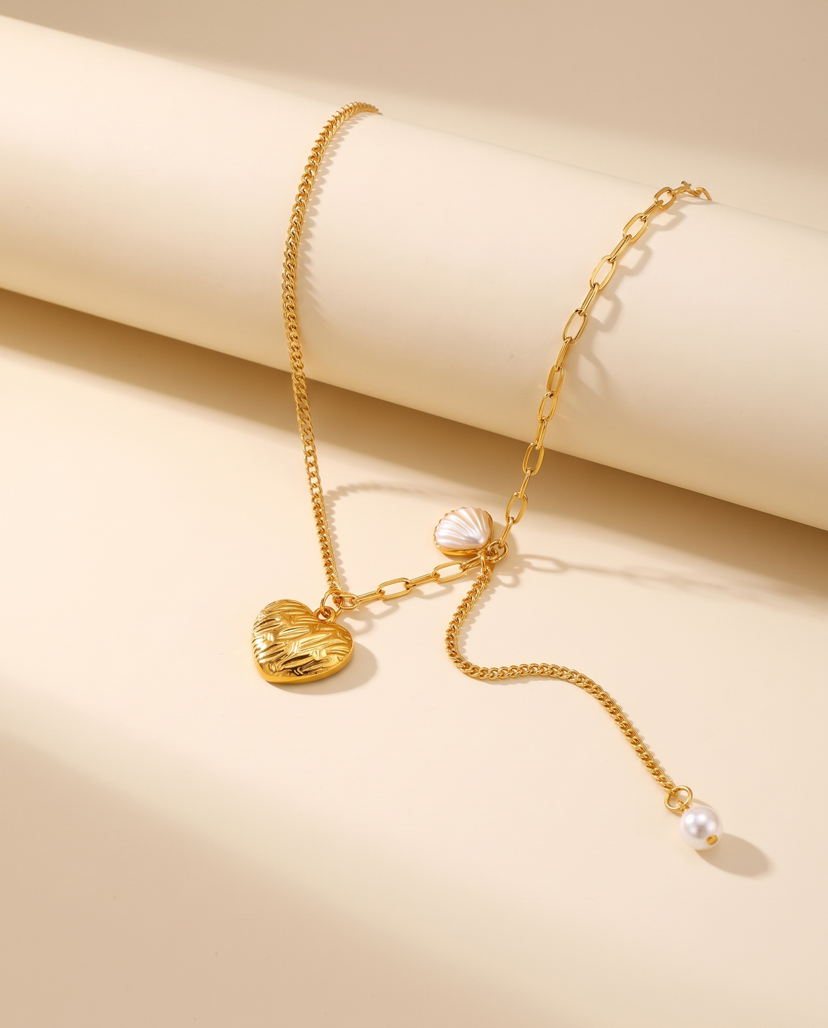 Love Pendant Tassel Necklace in gold — stainless steel with 18K gold plating, on a plain ground.
